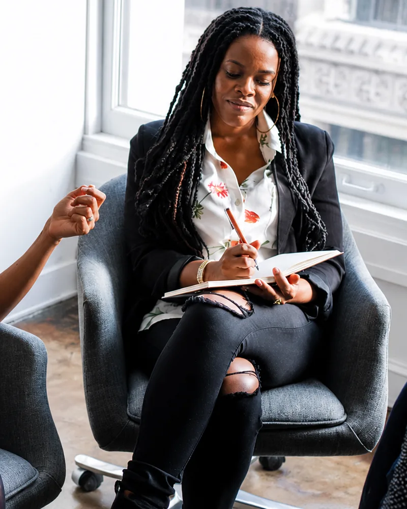 A woman taking notes in a notebook during a one to one session